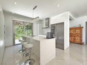 A modern kitchen with a central island, stainless steel appliances, and a wooden cabinet.