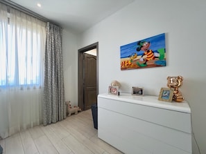 Ein Zimmer mit einem weißen Schminktisch, einem Bild mit einer Comicfigur und einem Teddybären.