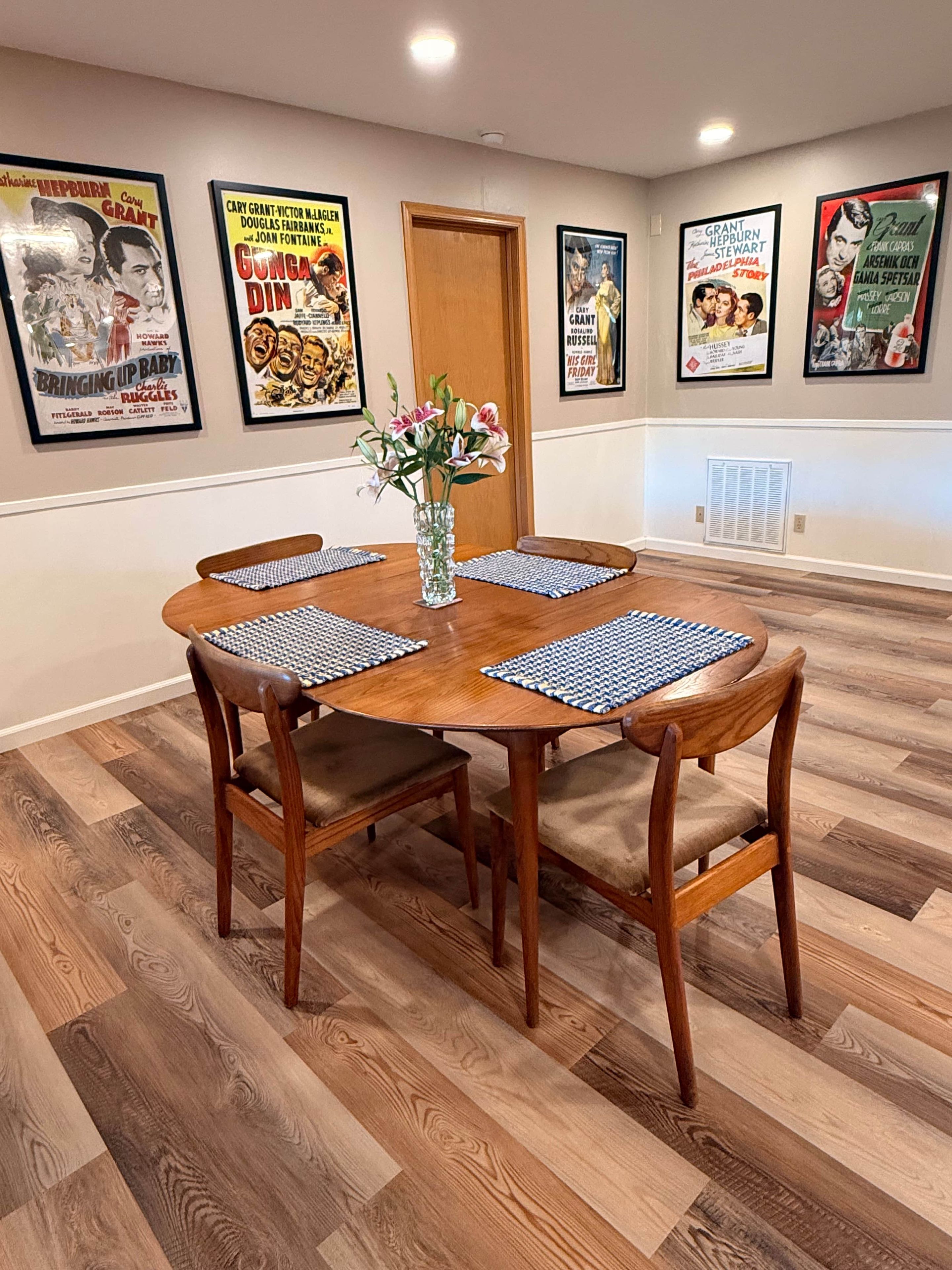 Une salle à manger avec une table et des chaises en bois, dont les murs sont ornés d’affiches de films encadrées.