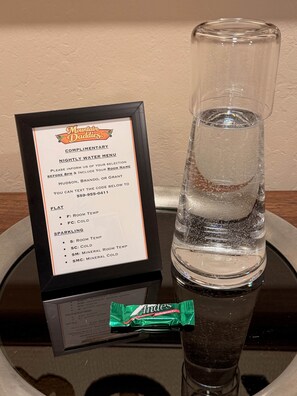 Cartel de menú de agua de cortesía, un vaso de agua y un paquete de caramelos Andes.