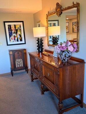 A wooden dresser with drawers, a mirror, a lamp, and a vase with flowers.