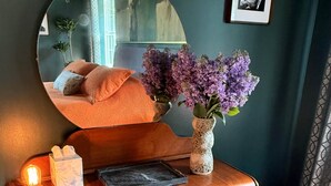 Ein hölzerner Waschtisch mit Spiegel, einer Blumenvase, einer Taschentuchbox und einem kleinen Hocker.