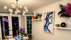 Ein Essbereich mit Holztisch, Stühlen, einer Chandelüster und einem Bild an der Wand.