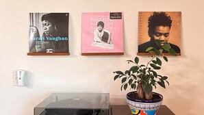 A wall with framed album covers, a turntable, and a bookshelf with magazines. - Hudson Queen Room at Mountain Daddies B&B (Oakhurst)