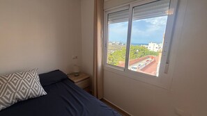 Una camera da letto con un letto, un comodino, una lampada e una finestra vista città.