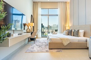 Et moderne hotelværelse med en stor seng, et skrivebord, et fladskærms-tv og udsigt over byen.