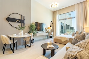 A modern living room with a dining area, a sofa set, a coffee table, and a large window. - Stylish Modern Studio with Community Views, Next to the Community Park (Dubai)