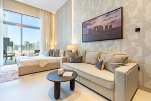 A modern hotel room with a large window, a sofa, a bed, and a coffee table. - Stylish Modern Studio with Community Views, Next to the Community Park (Dubai)