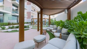 A modern outdoor lounge area with seating, a pergola, and a view of residential buildings. - Stylish Modern Studio with Community Views, Next to the Community Park (Dubai)