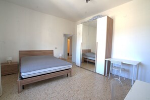A bedroom with a bed, a desk, and a mirror. - 118 m2 apartment, ideal for up to 7 people, on the 2nd floor of a building with lift.Located in San Giuliano Mare, north of the canal port and a few minutes from the historic center, it enjoys a strategic position that allows you to easily reach the beac (Rimini)