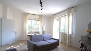 A room with a sofa, a radiator, a window, and a door. - 118 m2 apartment, ideal for up to 7 people, on the 2nd floor of a building with lift.Located in San Giuliano Mare, north of the canal port and a few minutes from the historic center, it enjoys a strategic position that allows you to easily reach the beac (Rimini)