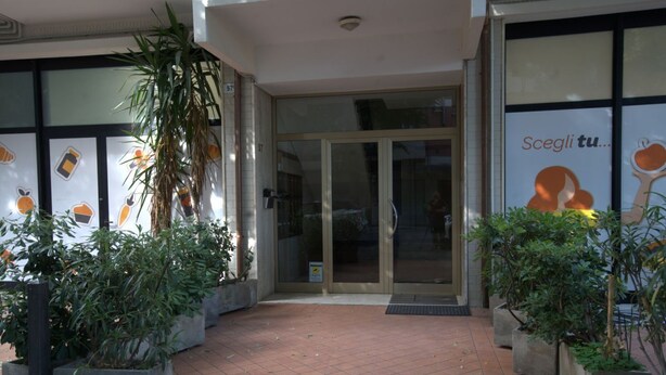 A building entrance with glass doors, potted plants, and a tiled pavement. - 118 m2 apartment, ideal for up to 7 people, on the 2nd floor of a building with lift.Located in San Giuliano Mare, north of the canal port and a few minutes from the historic center, it enjoys a strategic position that allows you to easily reach the beac (Rimini)