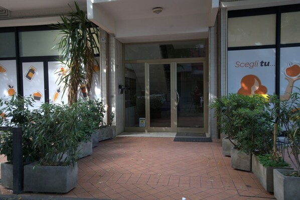 A building entrance with glass doors, potted plants, and a tiled pavement. - 118 m2 apartment, ideal for up to 7 people, on the 2nd floor of a building with lift.Located in San Giuliano Mare, north of the canal port and a few minutes from the historic center, it enjoys a strategic position that allows you to easily reach the beac (Rimini)