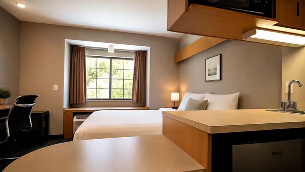 A hotel room with a bed, desk, chair, lamp, window with curtains, and a sink. - Cozy Sturbridge Home Next Old Village Breakfast (Sturbridge)