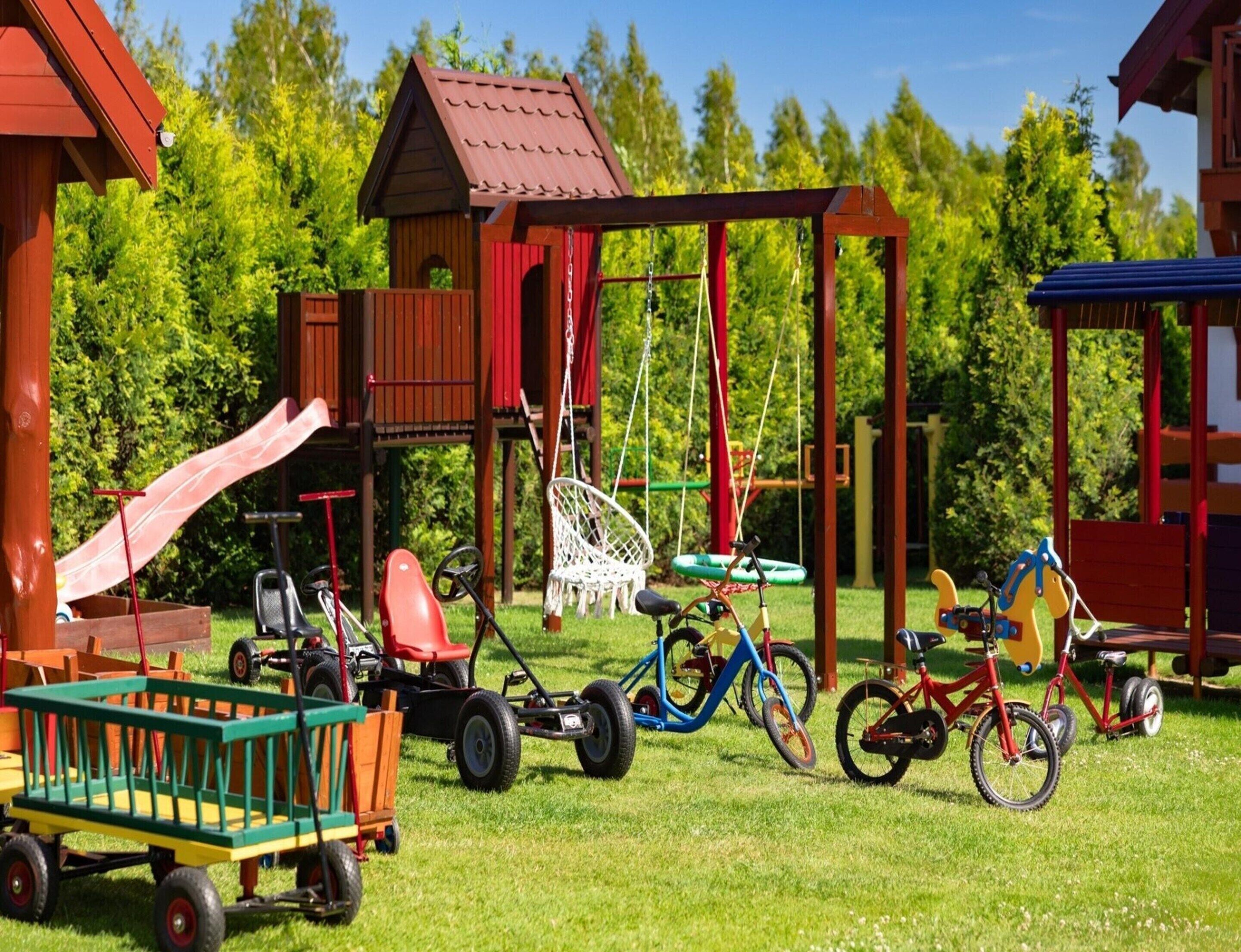 A playground with a slide, swings, and a small house structure.