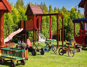 Ein Spielplatz mit Rutsche, Schaukeln und einer kleinen Häuserbau.