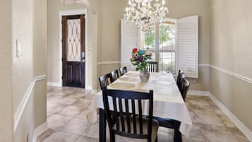 Uma área de jantar com uma mesa posta para quatro pessoas, um candelabro e um vaso com flores.