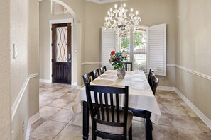 Uma área de jantar com uma mesa posta para quatro pessoas, um candelabro e um vaso com flores.
