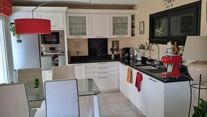 A modern kitchen with white cabinets, a black countertop, and a red espresso machine. - Beautiful apartment with a piano (Sainte-Maxime)