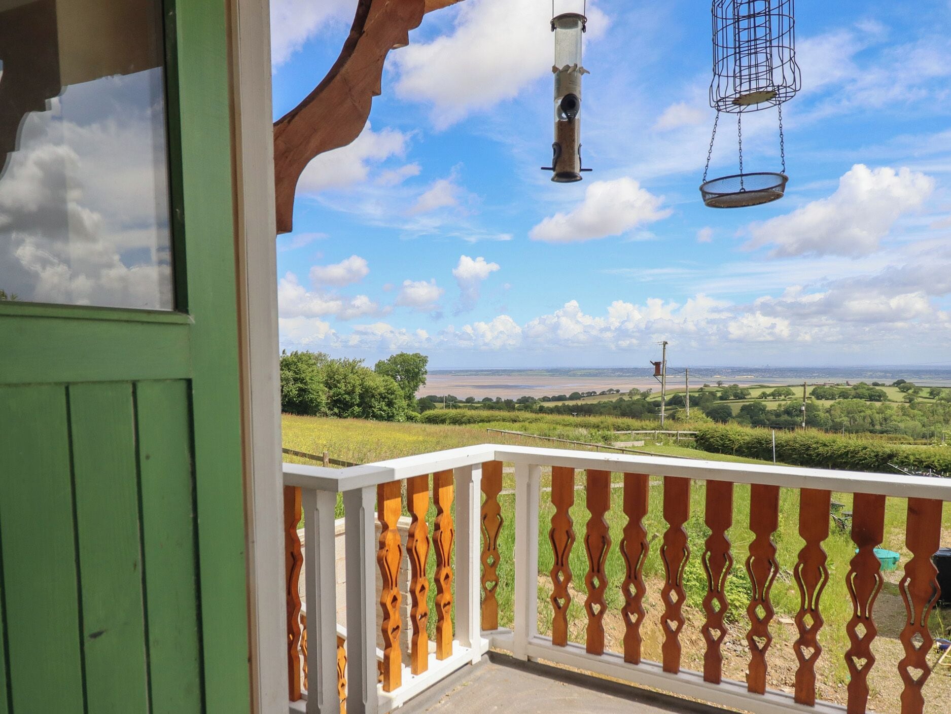 A balcony with a view of a green landscape and a clear sky.