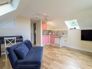 A modern loft with a dining area, a kitchenette, a sofa, and a TV. - Hay Loft at Ebenezer Chapel (Holywell)