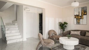 A modern living room with a marble staircase, a round coffee table, and a large abstract painting.