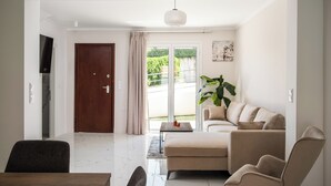 A living room with a sofa, armchairs, a coffee table, and a TV.
