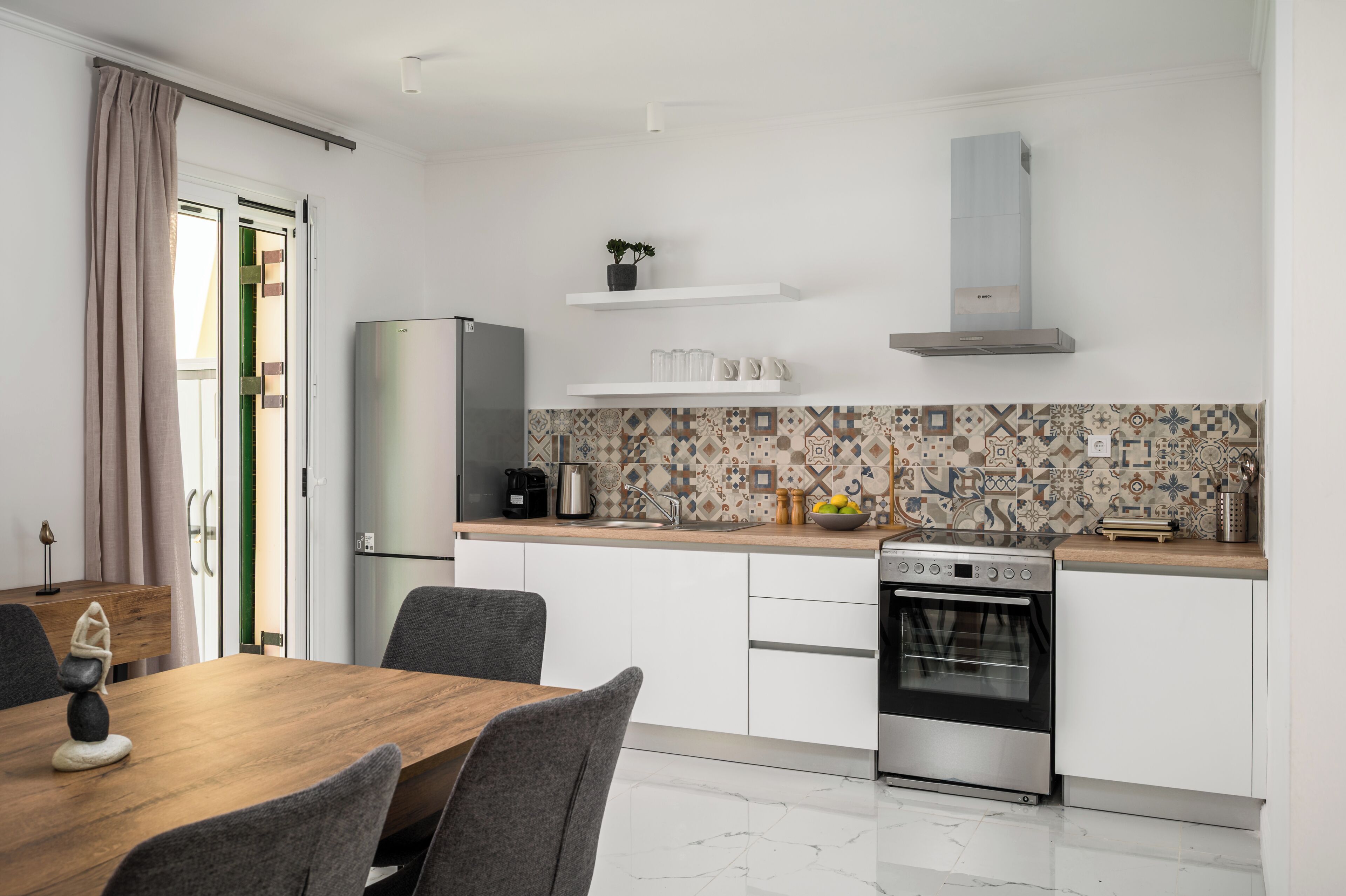 Een compacte keuken met een modern ontwerp, voorzien van een ingebouwde oven, een koelkast en een betegelde spatwand.