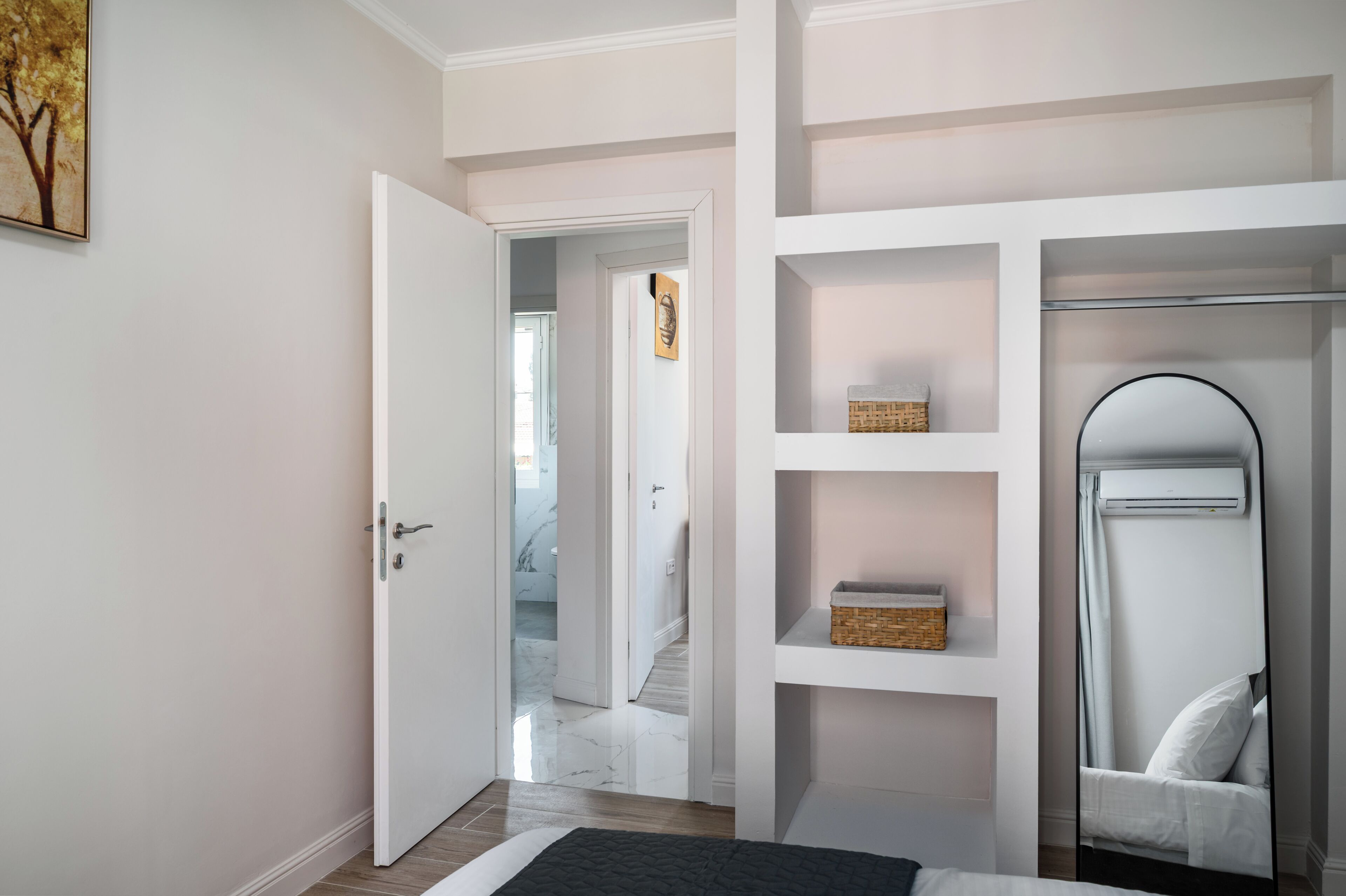 Een slaapkamer met een bed, een garderobe, een spiegel en een deur naar een badkamer.