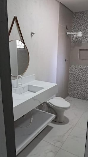 Un baño con lavamanos, espejo y retrete blancos.
