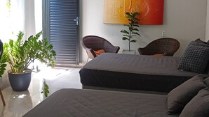 A modern bedroom with a bed, two chairs, a potted plant, and a large abstract painting on the wall. - Garden Monte Líbano (Rondonópolis)