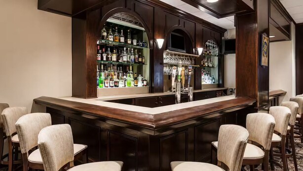 Un'area bar con un bancone, diversi posti a sedere e scaffali pieni di bottiglie.