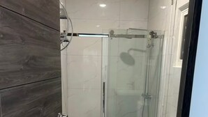A modern bathroom with a glass-enclosed shower, a white toilet, and a vanity with a mirror. - Belair Pool Villa w/ Rooftop & Island Views Oasis (Little Bay)