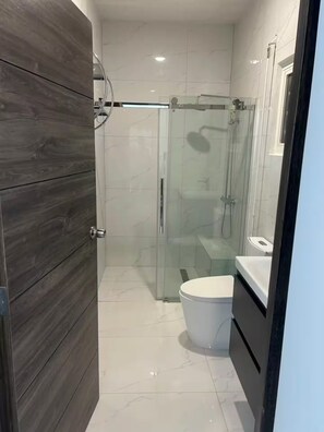 A modern bathroom with a glass-enclosed shower, a white toilet, and a vanity with a mirror. - Belair Pool Villa w/ Rooftop & Island Views Oasis (Little Bay)