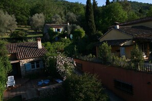 A traditional villa with a tiled roof, stone walls, and a garden with a patio area.