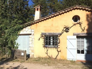 Un bâtiment rustique avec un mur en pierre, une clôture en bois et une fenêtre dotée de volets à barreaux.