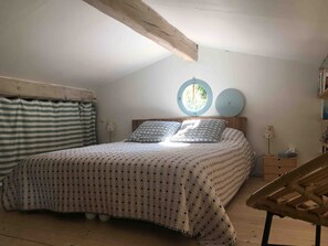 Une chambre avec un lit, une fenêtre, un élément de décoration murale rond et une chaise.