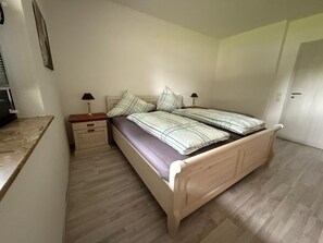 Ein Einzelbett mit Kopfteil, Nachttischen und Holzboden.