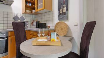A kitchen with a round table, two chairs, a tray with a bottle, glasses, and a card.