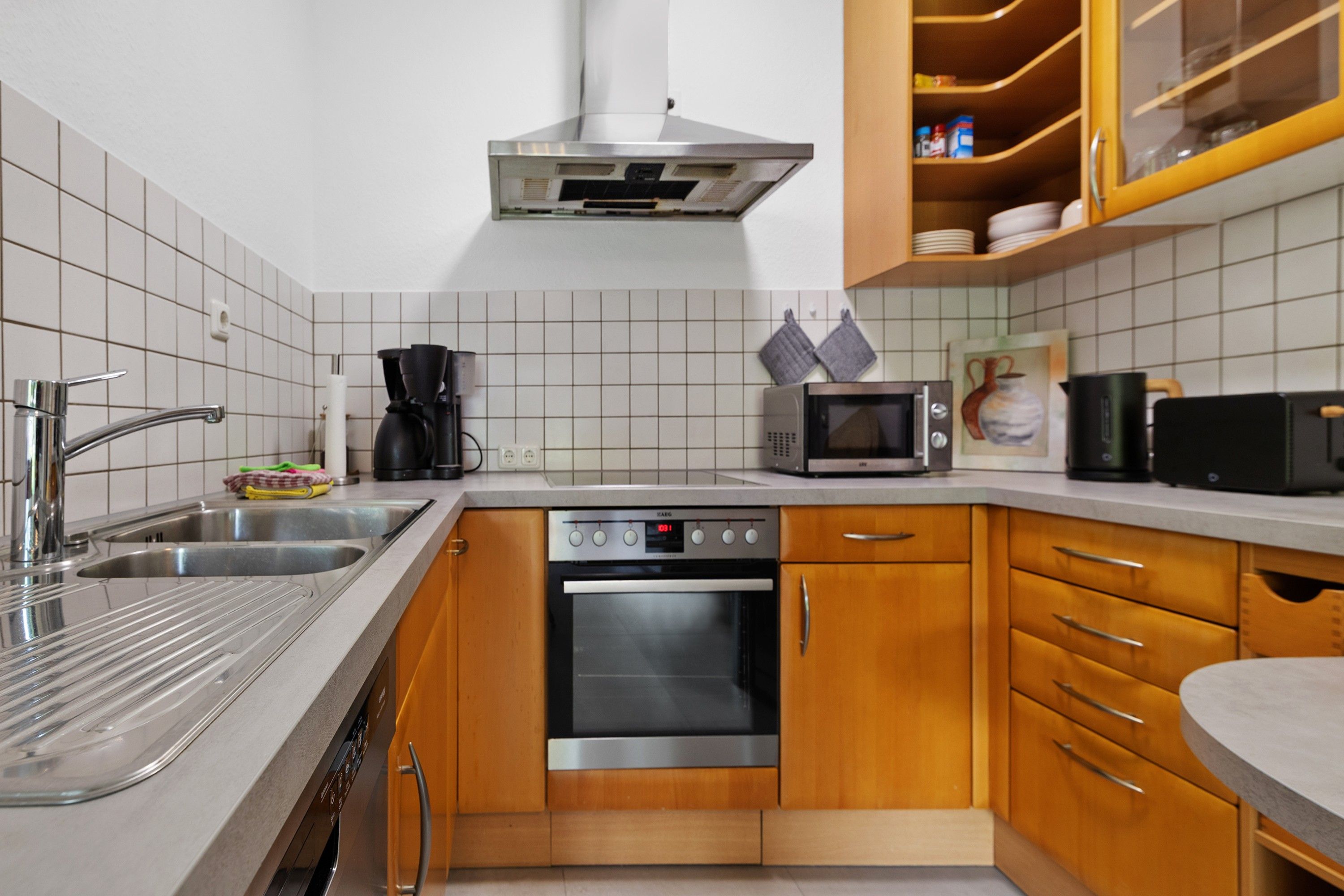 A kitchen with a stainless steel sink, a microwave, an oven, and wooden cabinets.