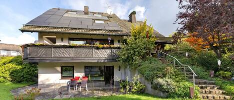 Une maison à deux étages avec un balcon, un jardin et un escalier menant à l’étage supérieur.