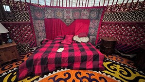 A room with a bed, a wooden nightstand, a patterned rug, and a decorative headboard.