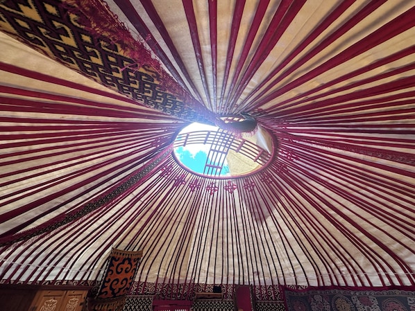 A circular skylight with a view of the sky, surrounded by a patterned ceiling.