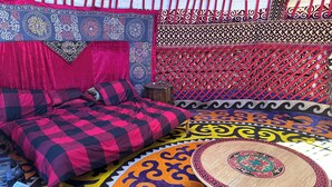 Una habitación con una cama, una pequeña mesa redonda y alfombras estampadas.