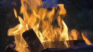 A campfire with logs and a metal container.
