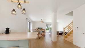 Una cucina moderna con un piano di lavoro in legno, un'area pranzo con sedie, una scala e una ventola a soffitto.