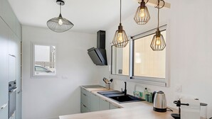 Una cucina moderna con un piano di lavoro in legno, forno integrato, lavello e lampade a sospensione.