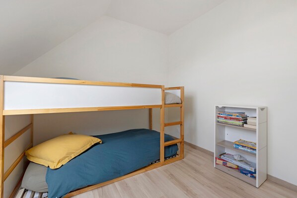 Una cama litera con una estantería a su lado.