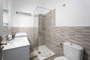 A modern bathroom with a glass-enclosed shower, a white sink, and a toilet. - Charming 1-bedroom Apartment With Ocean View in Arona (Arona)