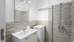 Un baño moderno con cabina de ducha de vidrio, un lavabo blanco y un espejo.